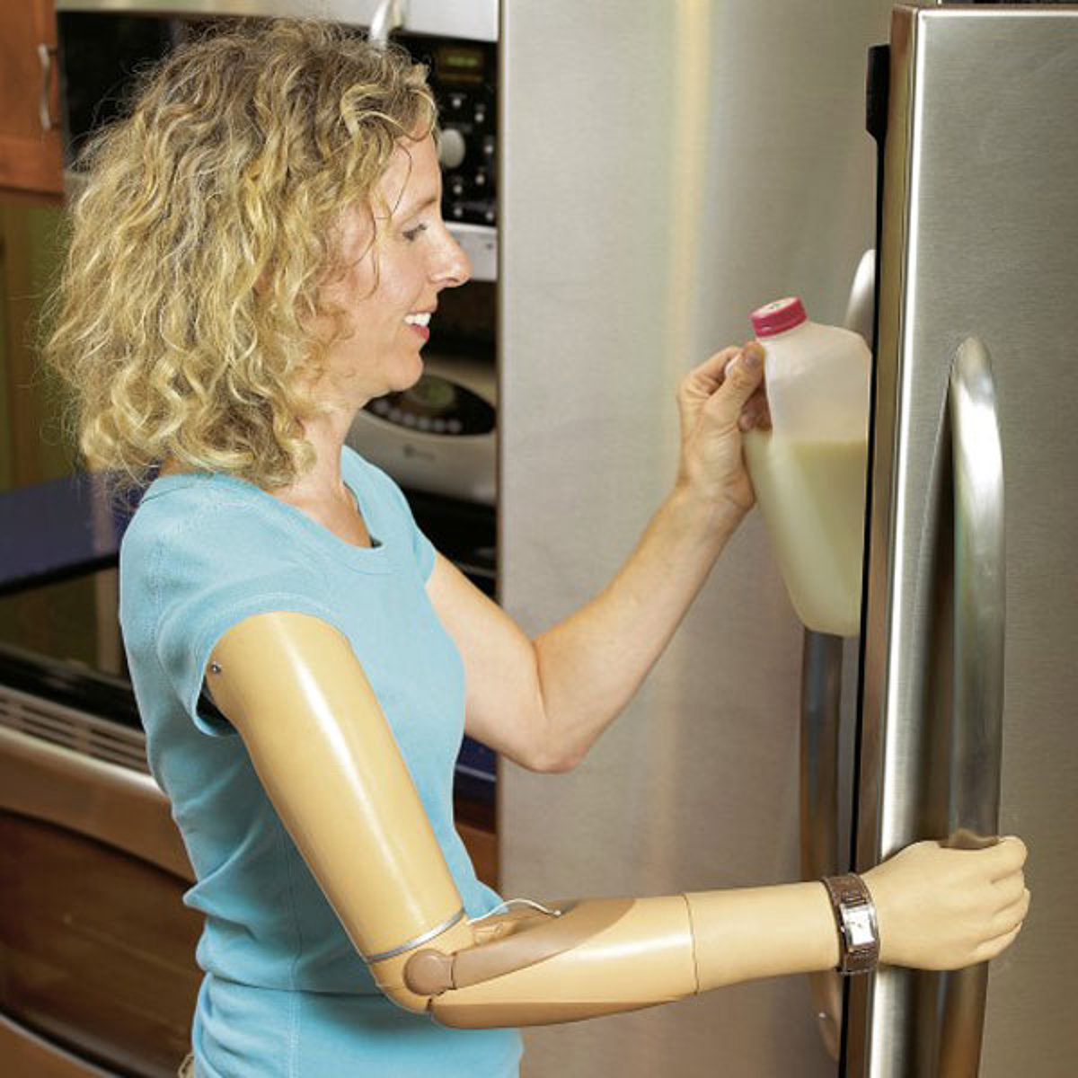 Eine Frau mit einer Armprothese öffnet einen Kühlschrank.