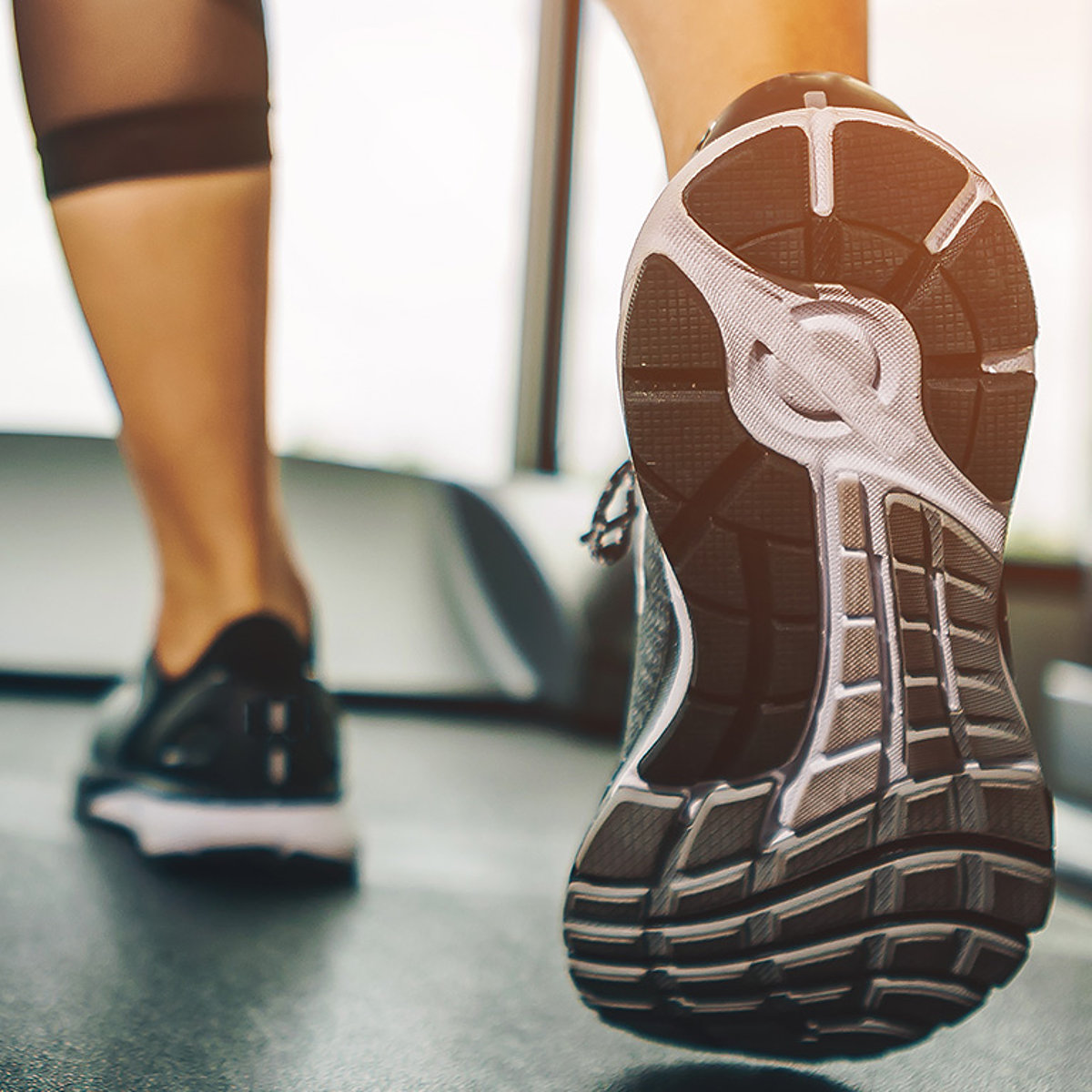 Eine Frau läuft mit maßangefertigten orthopädischen Schuhen auf einem Laufband. 