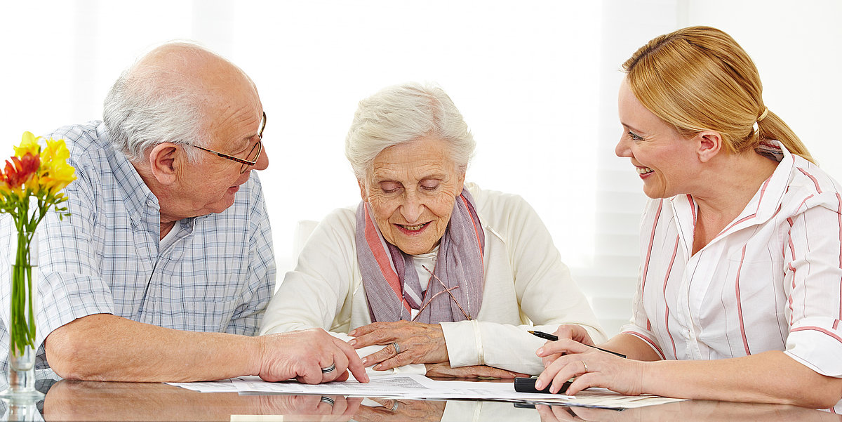 Ein älteres Ehepaar führt ein Beratungsgespräch mit einer Mitarbeiterin des Pflegedienstes.