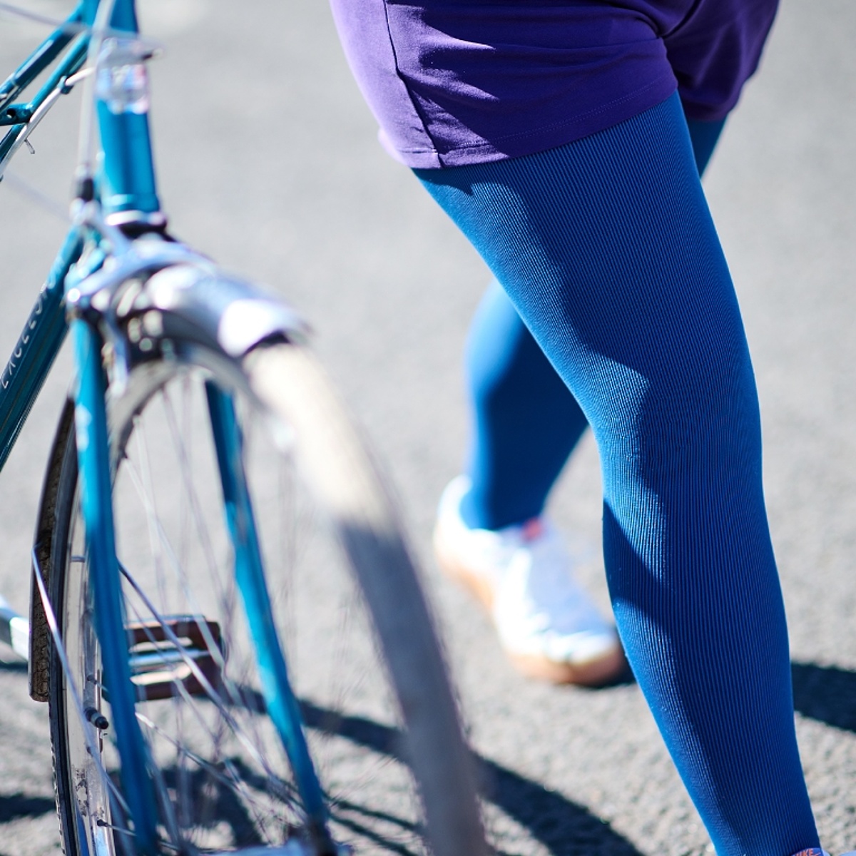 Beine, die eine Kompressionsleggins tragen, schieben ein Fahrrad.