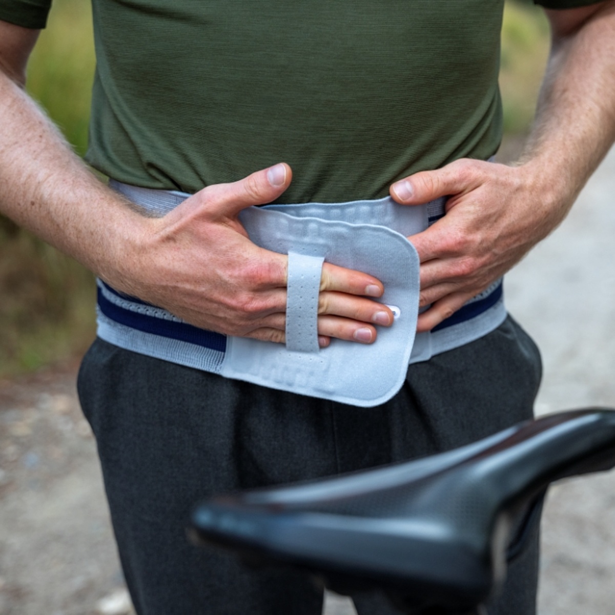 Eine Person steht vor einem Fahrrad und zieht eine Wirbelsäulenbandage an.