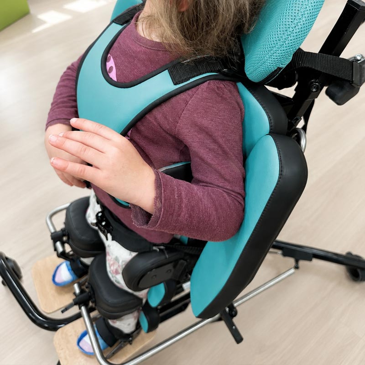 Kind in einem individuell angepassten Stehgerät mit gepolsterter Rumpf-, Becken- und Beinstütze im Bereich Kinder-Reha des KRIEGER Sanitätshauses