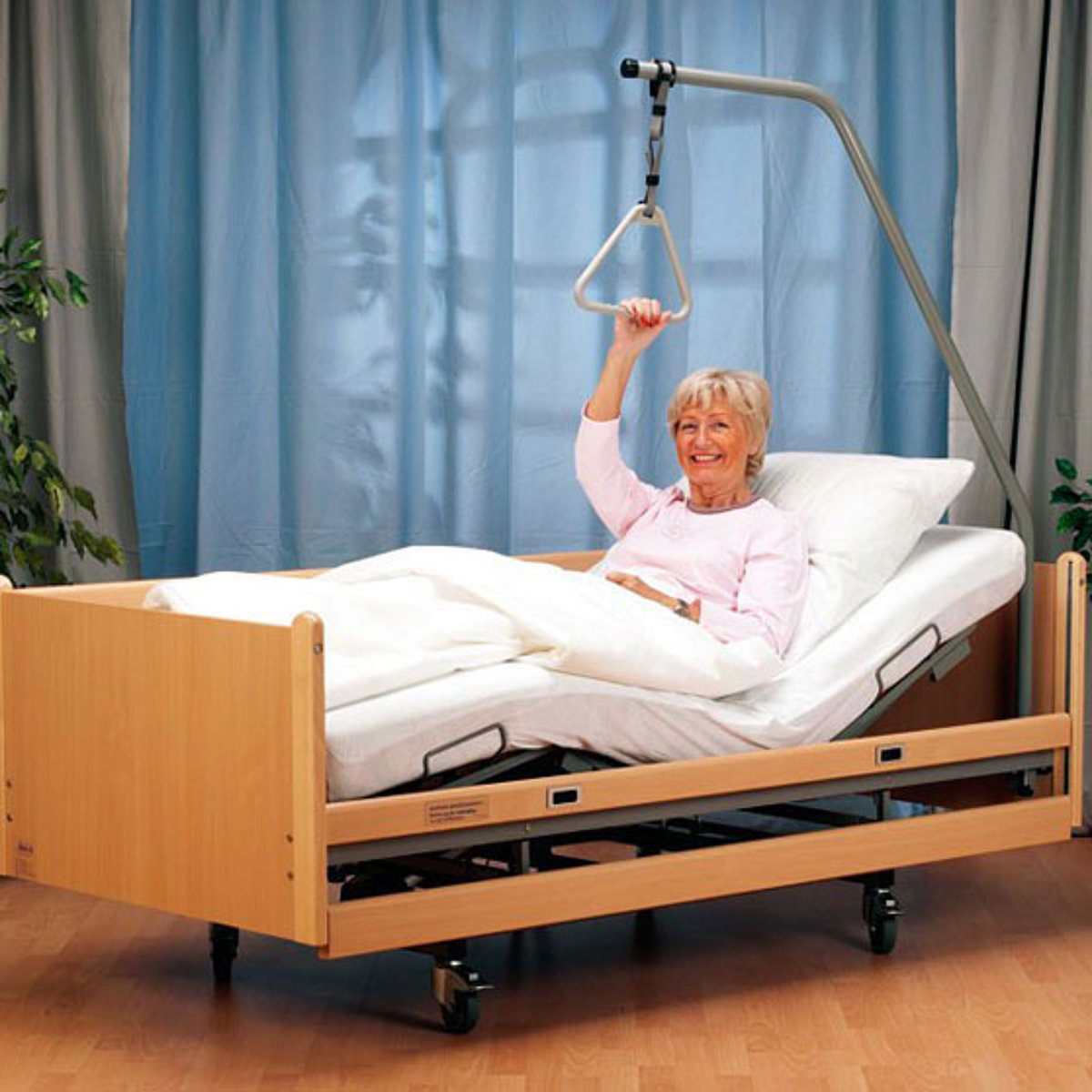 Eine Frau sitzt in einem Pflegebett und lächelt in die Kamera.