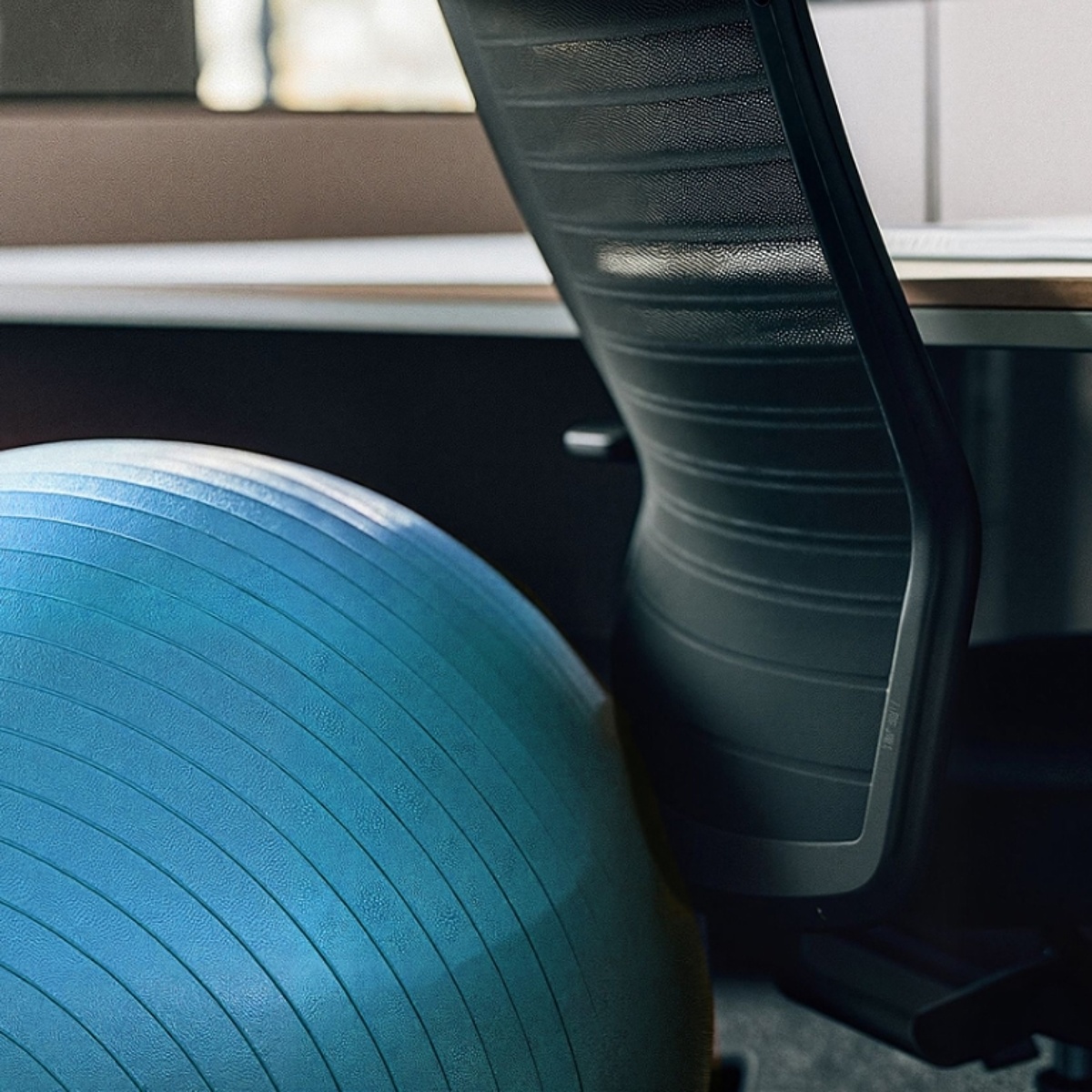 Ein Gymnastikball neben einem Bürostuhl.