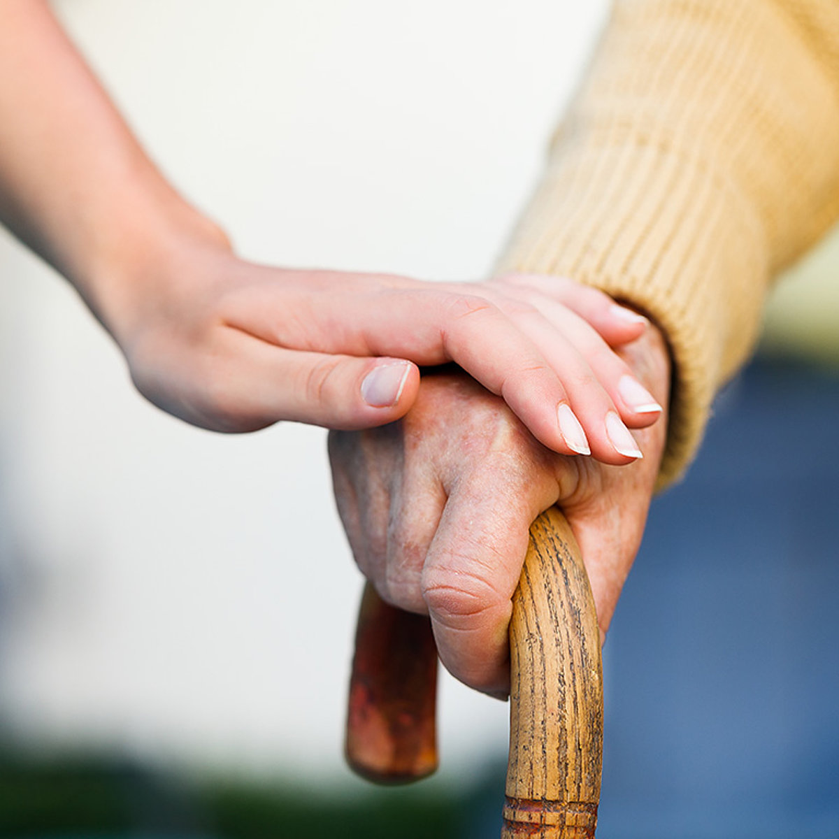 Eine Pflegerin berührt die Hand eines alten Mannes.