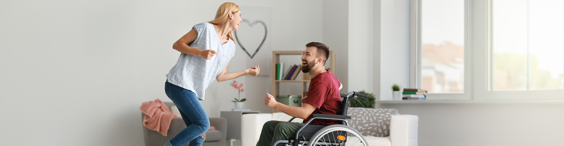 Eine Frau tanzt mit ihrem Mann, der im Rollstuhl stitz.
